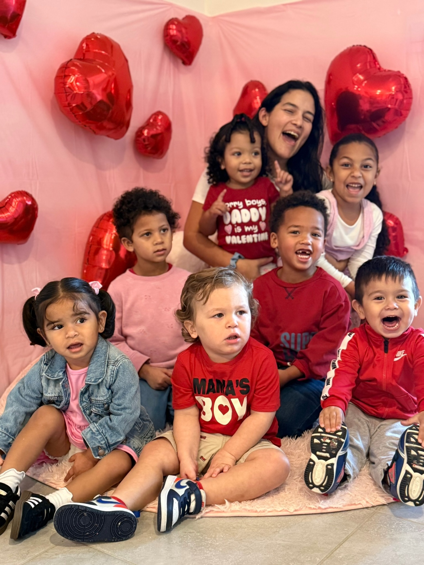 Group of children and teacher posing with red heart balloons for Valentine's Day