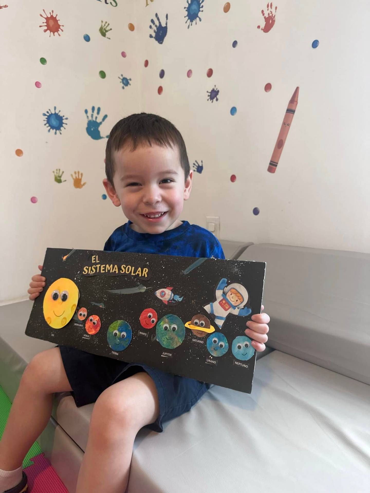 Smiling child showing a handmade solar system project