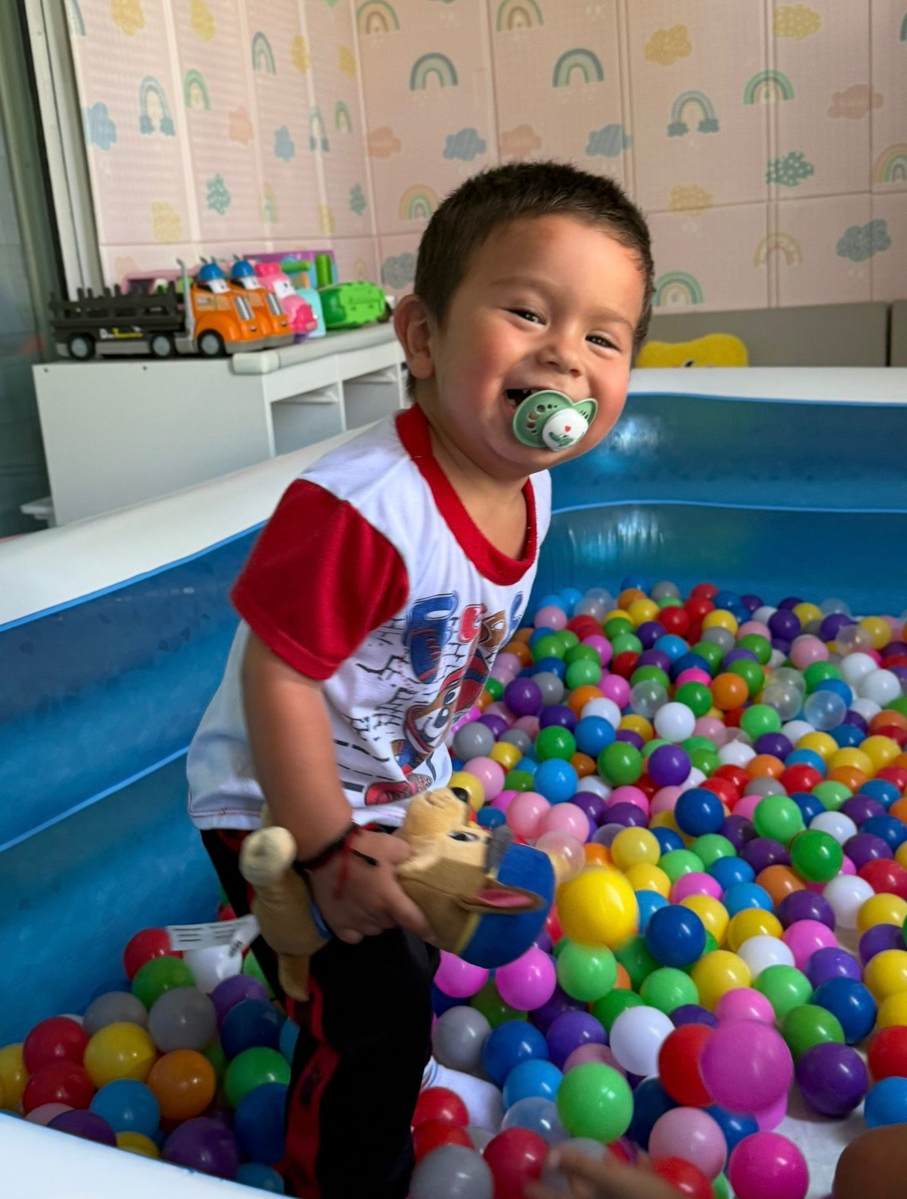 Smiling toddler playing in a colorful ball pit